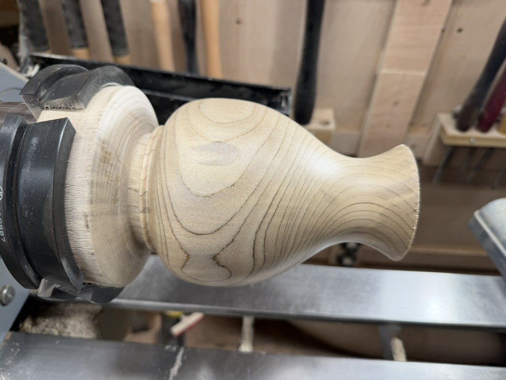 The vase shaped on the lathe, the grain flowing up into the neck