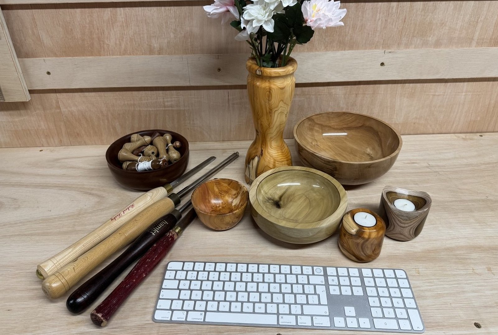 A hand-turned wooden bowl alongside a keyboard and turning tools